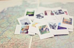 Quelle: Leah Newhouse / Pexels Mehrere Polaroid-Fotos liegen verstreut auf einer Landkarte
